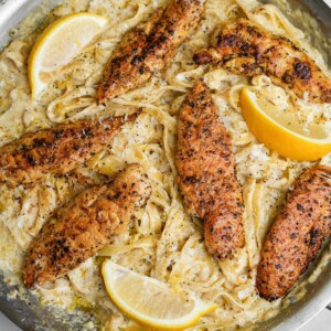 lemon pepper chicken on fettuccine alfredo in a pan