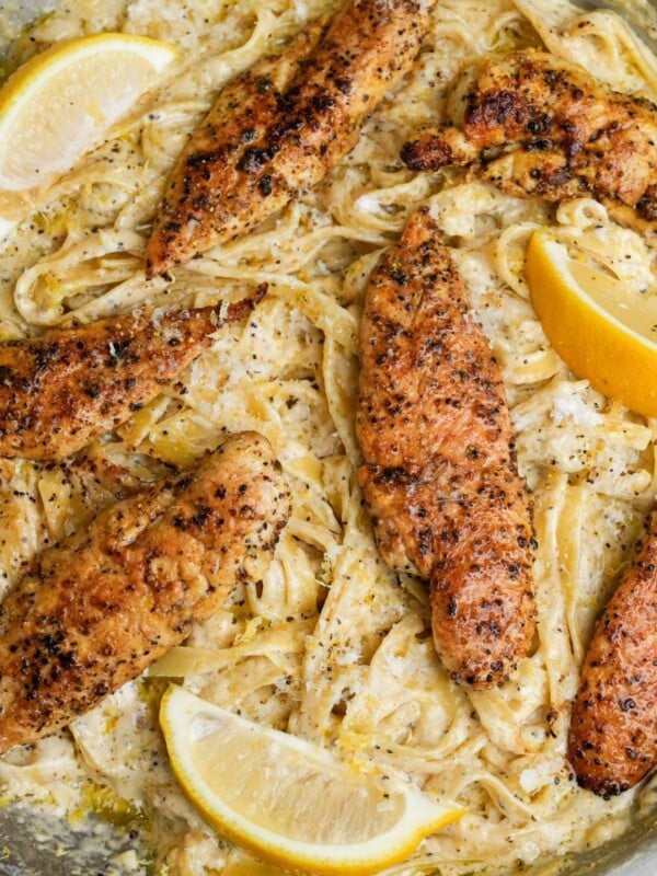 lemon pepper chicken on fettuccine alfredo in a pan