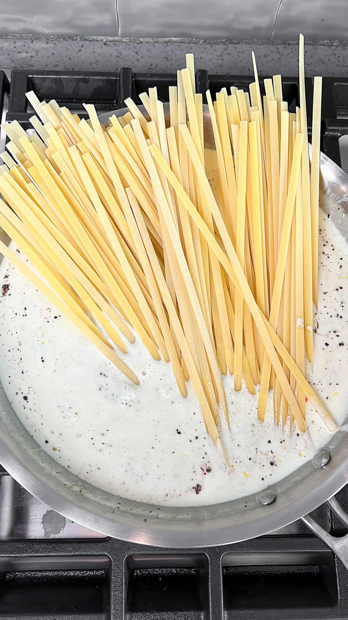 pasta placed in the alfredo pan sauce