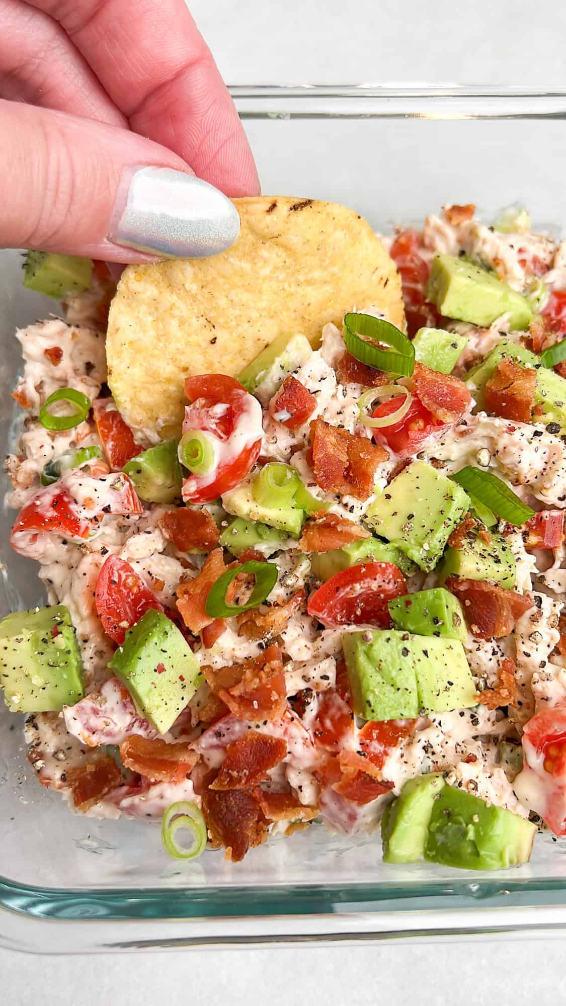 chicken salad in a bowl being picked up by a chip