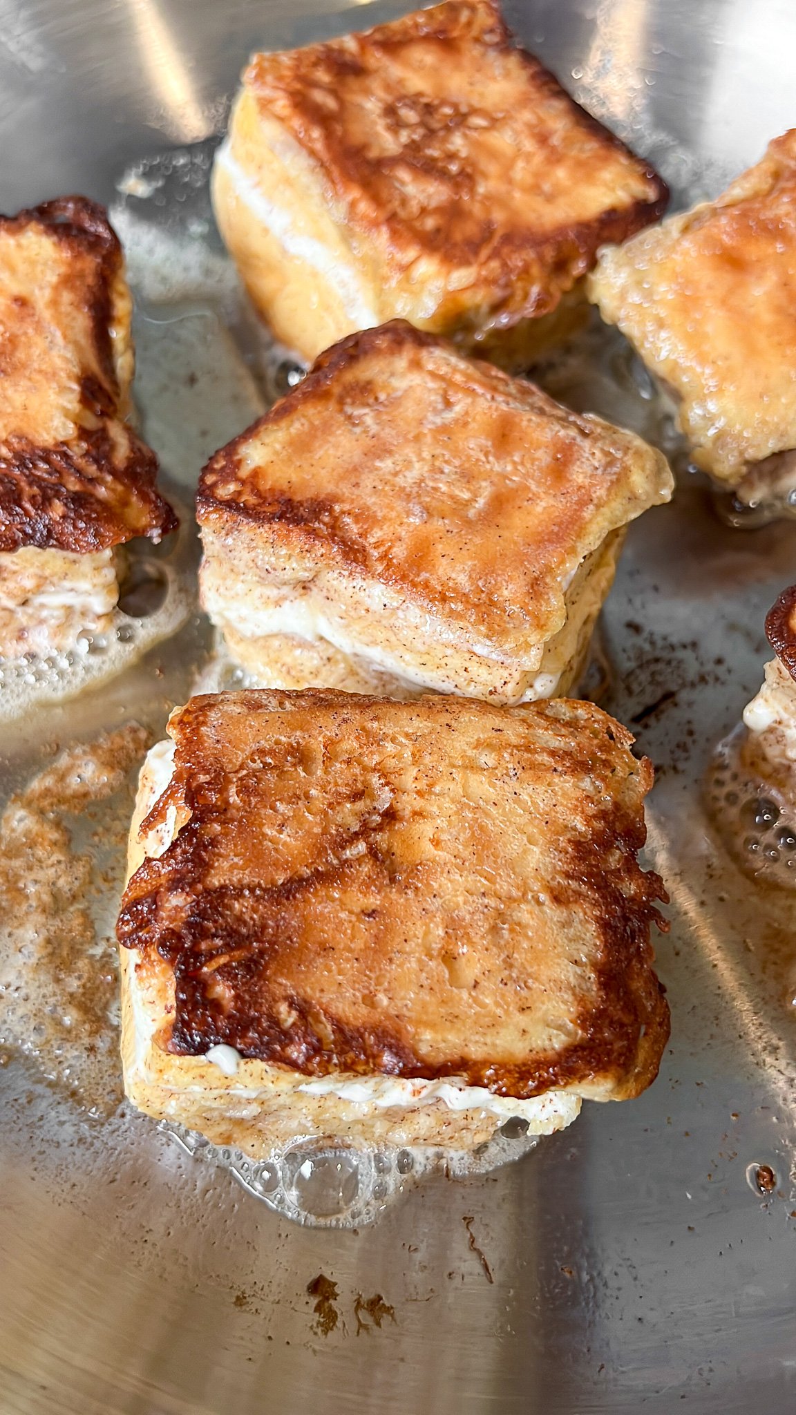 hawaiian roll french toast cooking in a pan