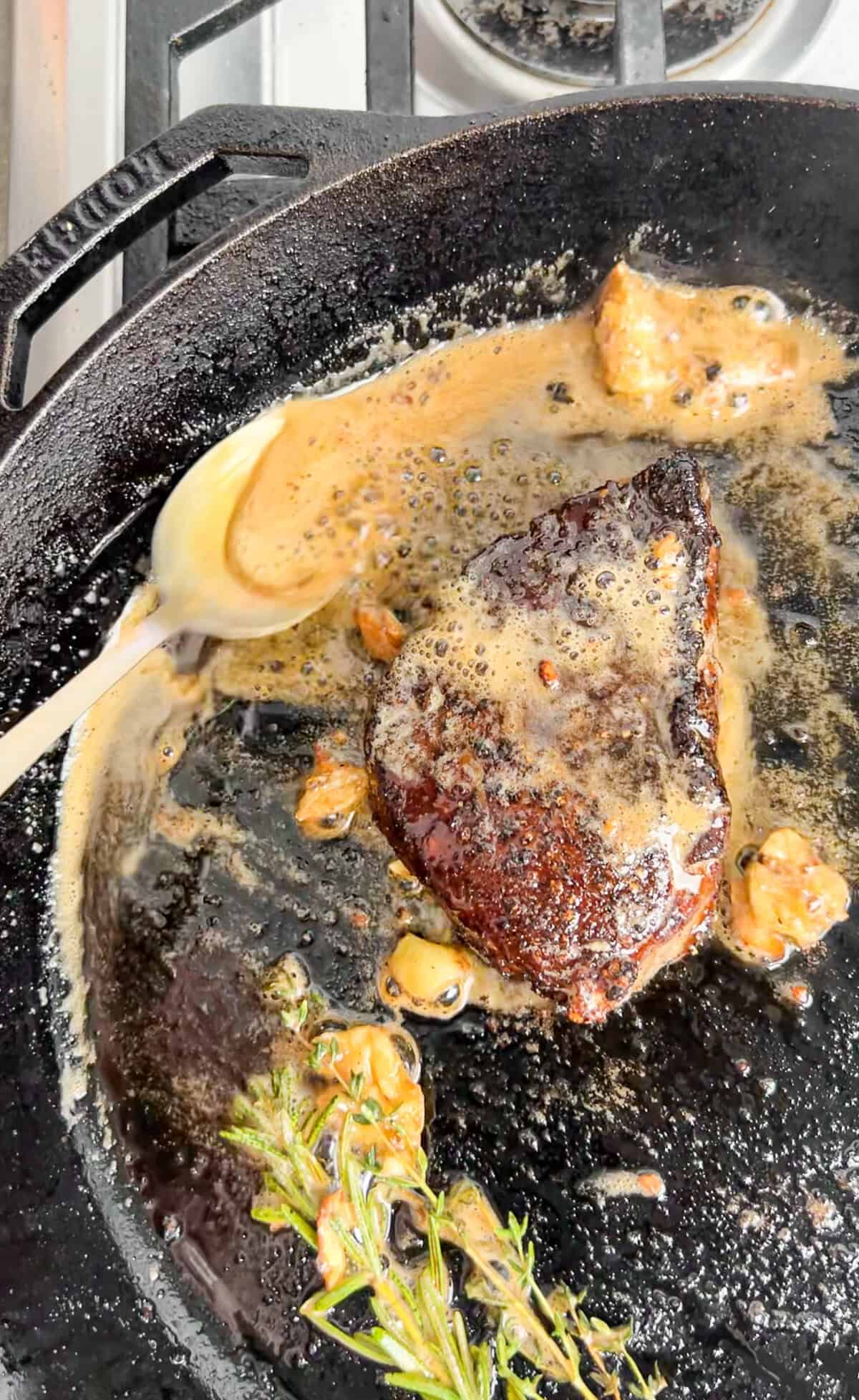 This cowboy butter is delicious smothered over juicy, tender ribeye steak! Full of tangy, herby flavors, lots of garlic, and a kick of heat. Seared steak basted with cowboy butter in a cast iron skillet.