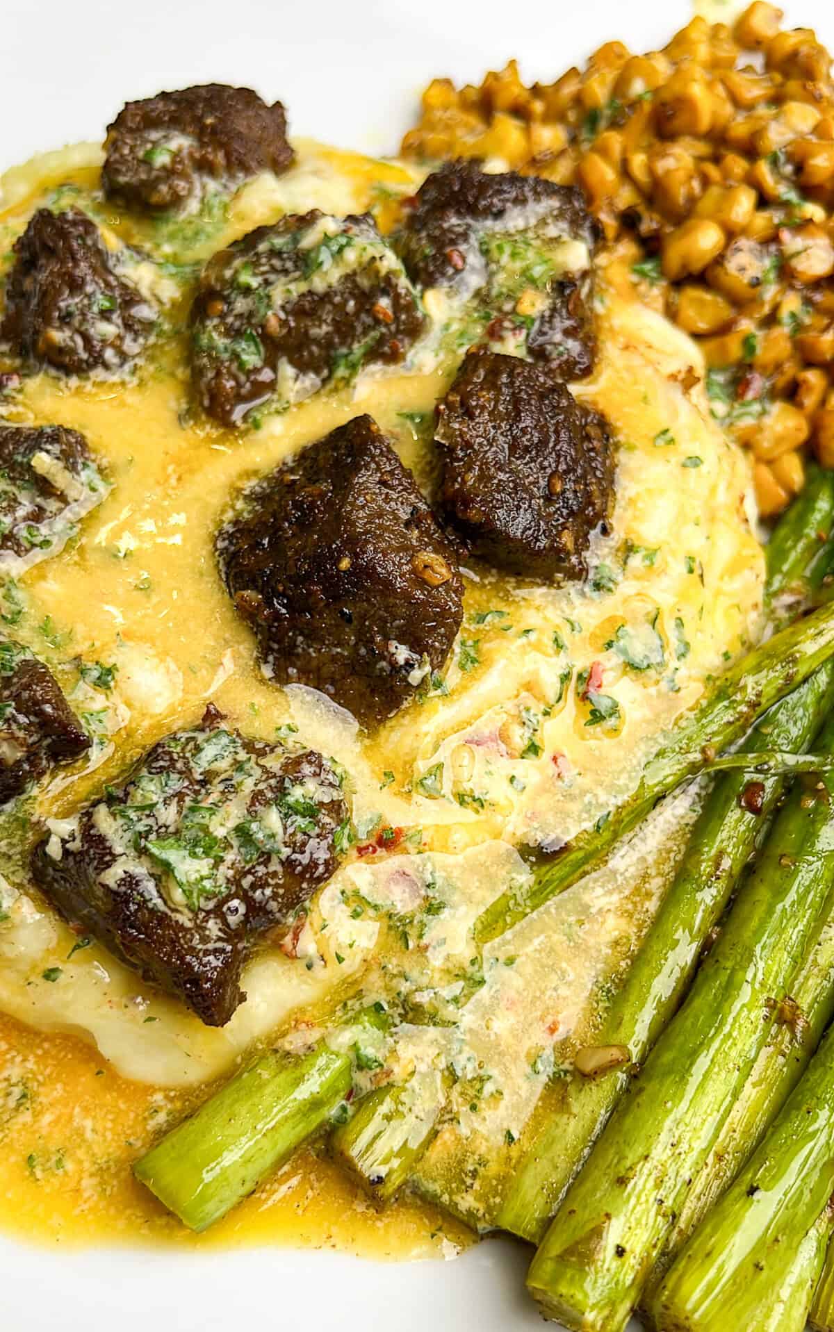 dinner plate with potatoes, steak, asparagus and corn drizzled with cowboy butter