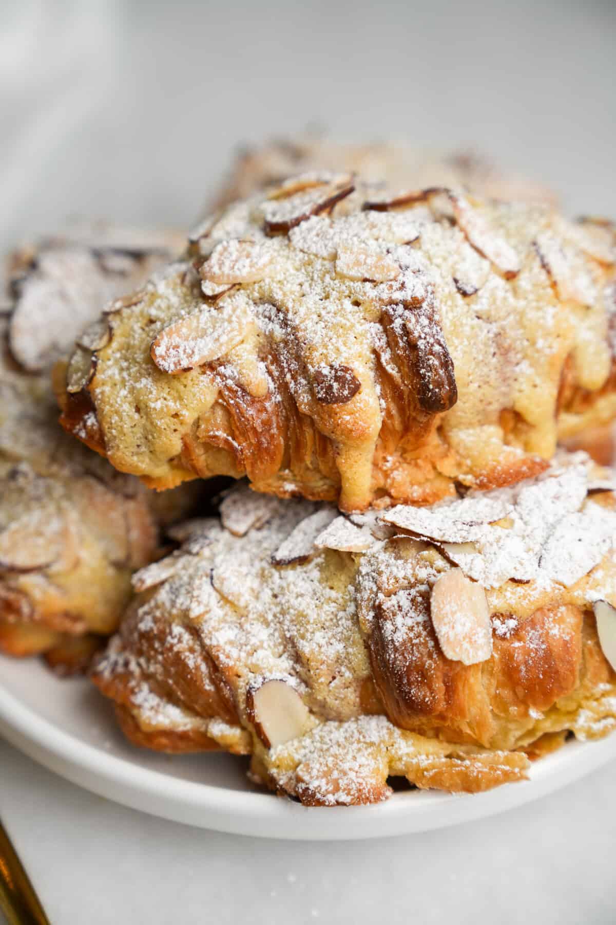 almond croissants dusted with powdered sugar on a plate