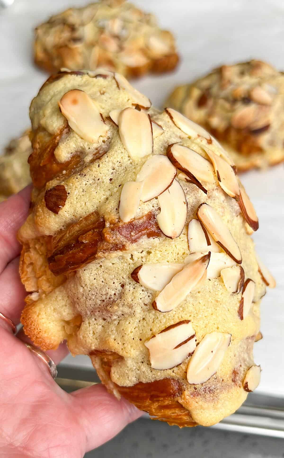 freshly baked almond croissants being held in hand