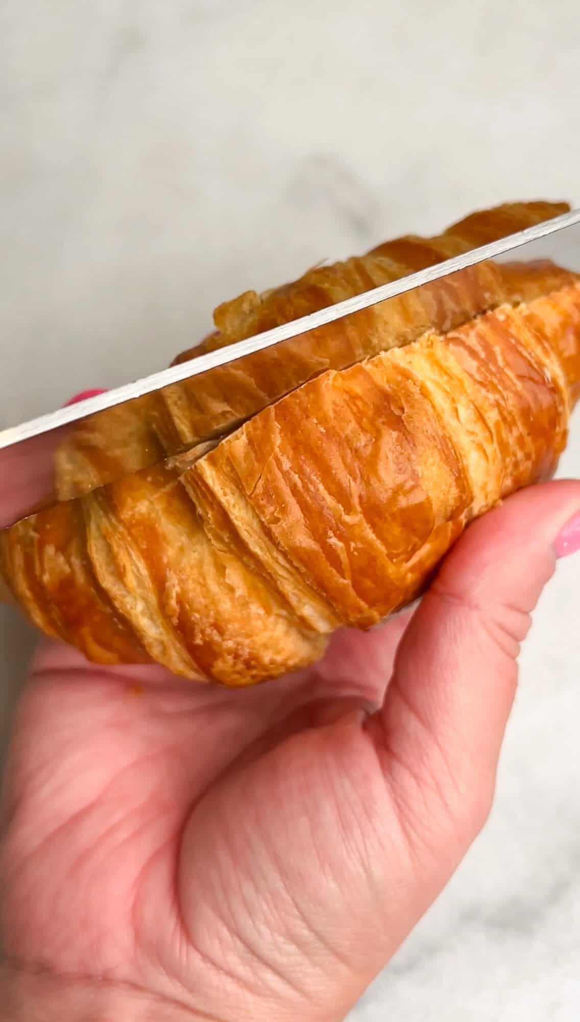 slicing open a croissant with a knife