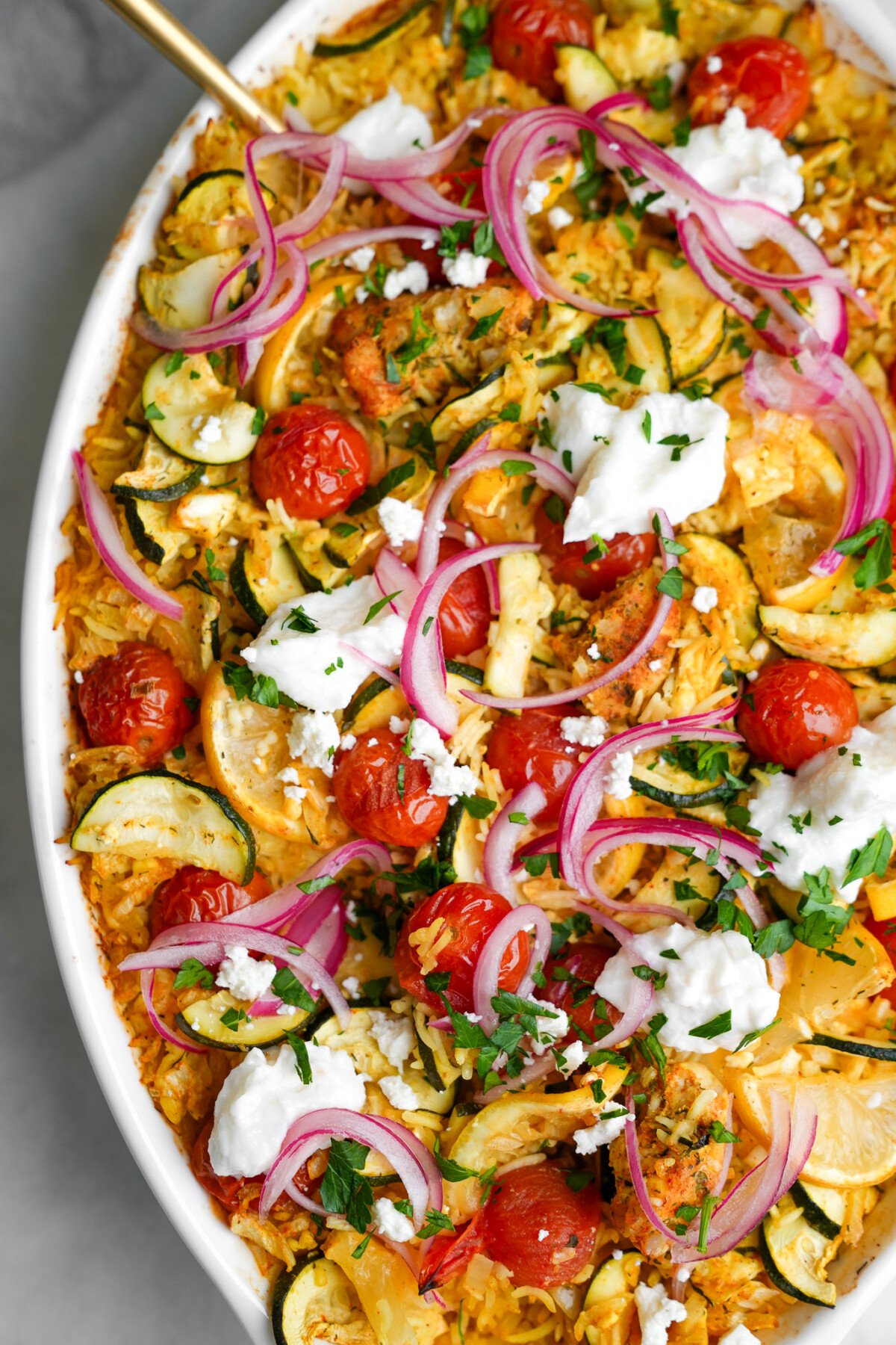 chicken tzatziki in a large casserole dish with a gold spoon