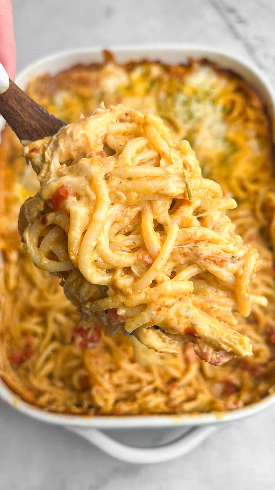 With tomatoes, cheese, juicy chicken, and a bit of heat, Chicken Spaghetti with Rotel is a dump-and-bake recipe that's ideal for weeknights. Chicken spaghetti with Rotel on a wooden spoon over the baking dish