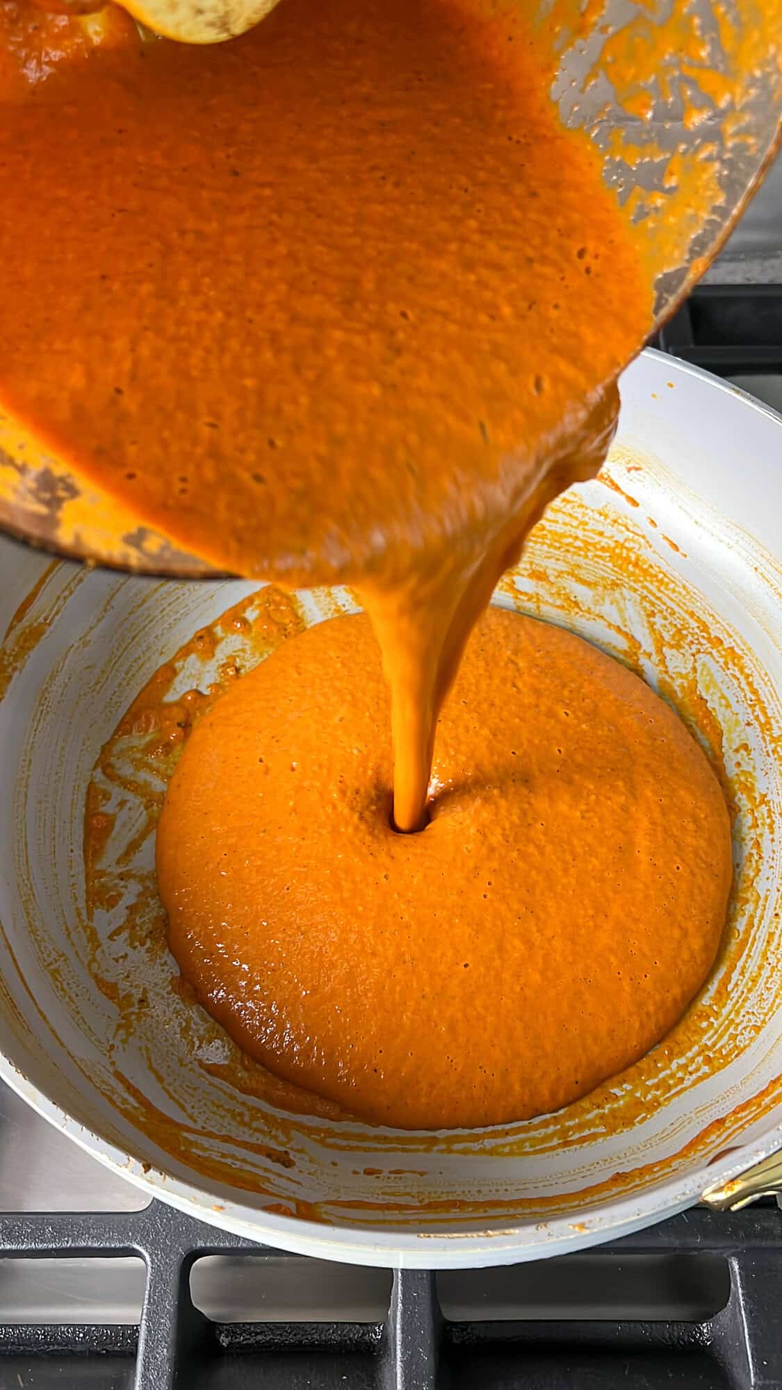pouring the butter chicken sauce into the pan