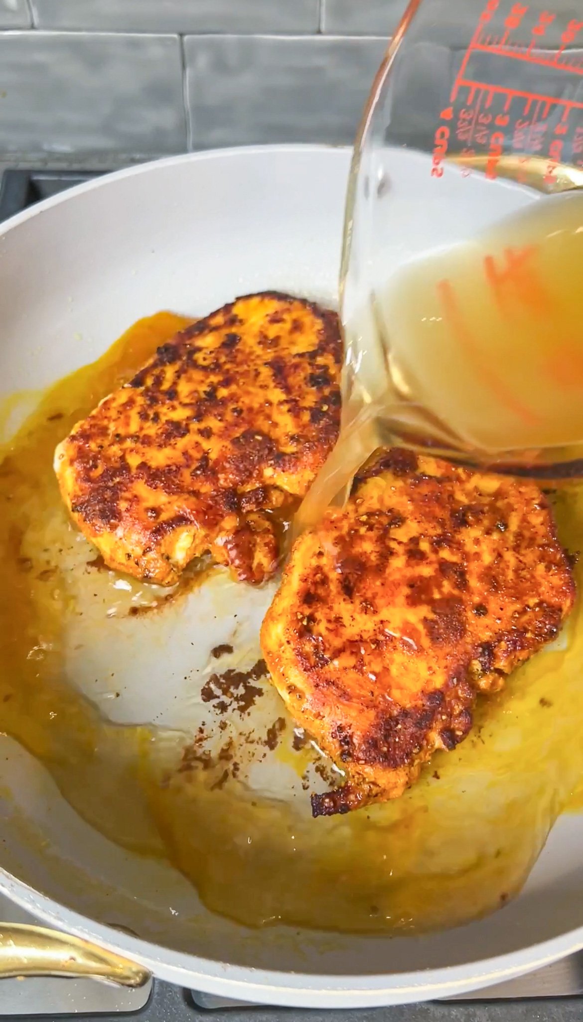 pouring chicken broth in a pan of chicken