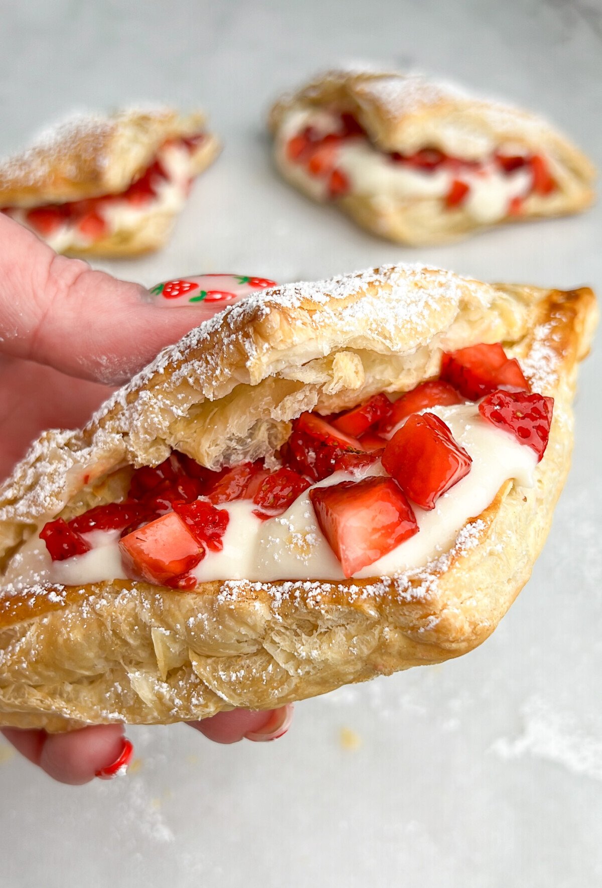 strawberry cheesecake pastry being held in hand