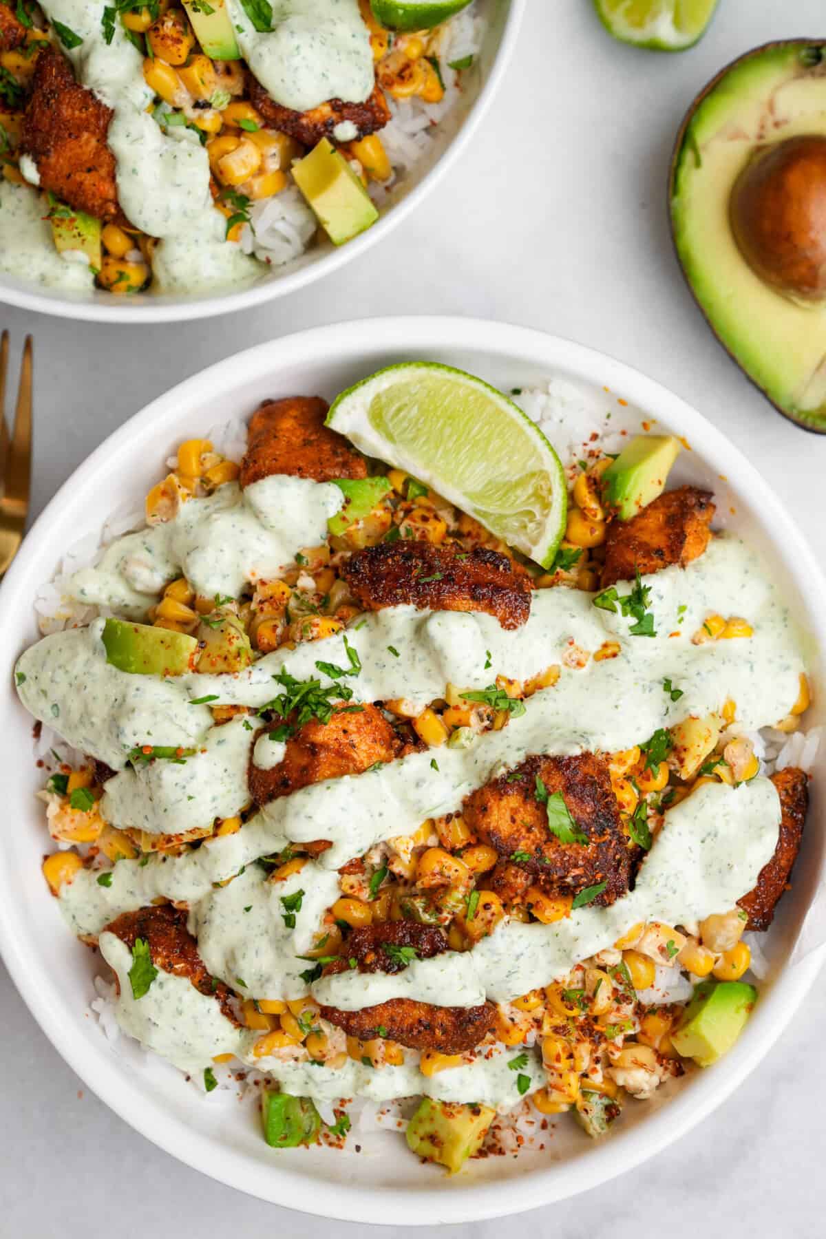 Overhead view of a rice bowl with chicken, street corn and creamy jalapeno sauce