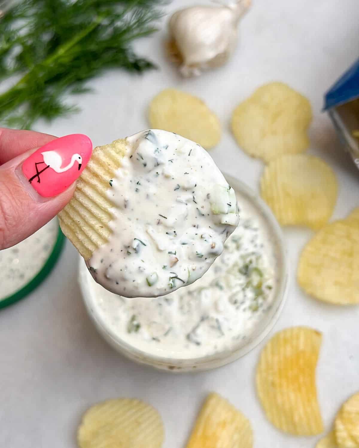 hand holding a chip dipped in ranch pickle dip