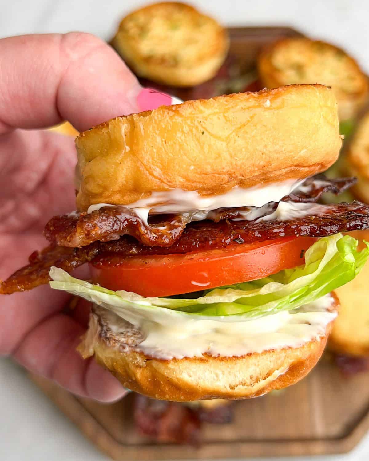 candied bacon blt slider sandwiches being held in hand