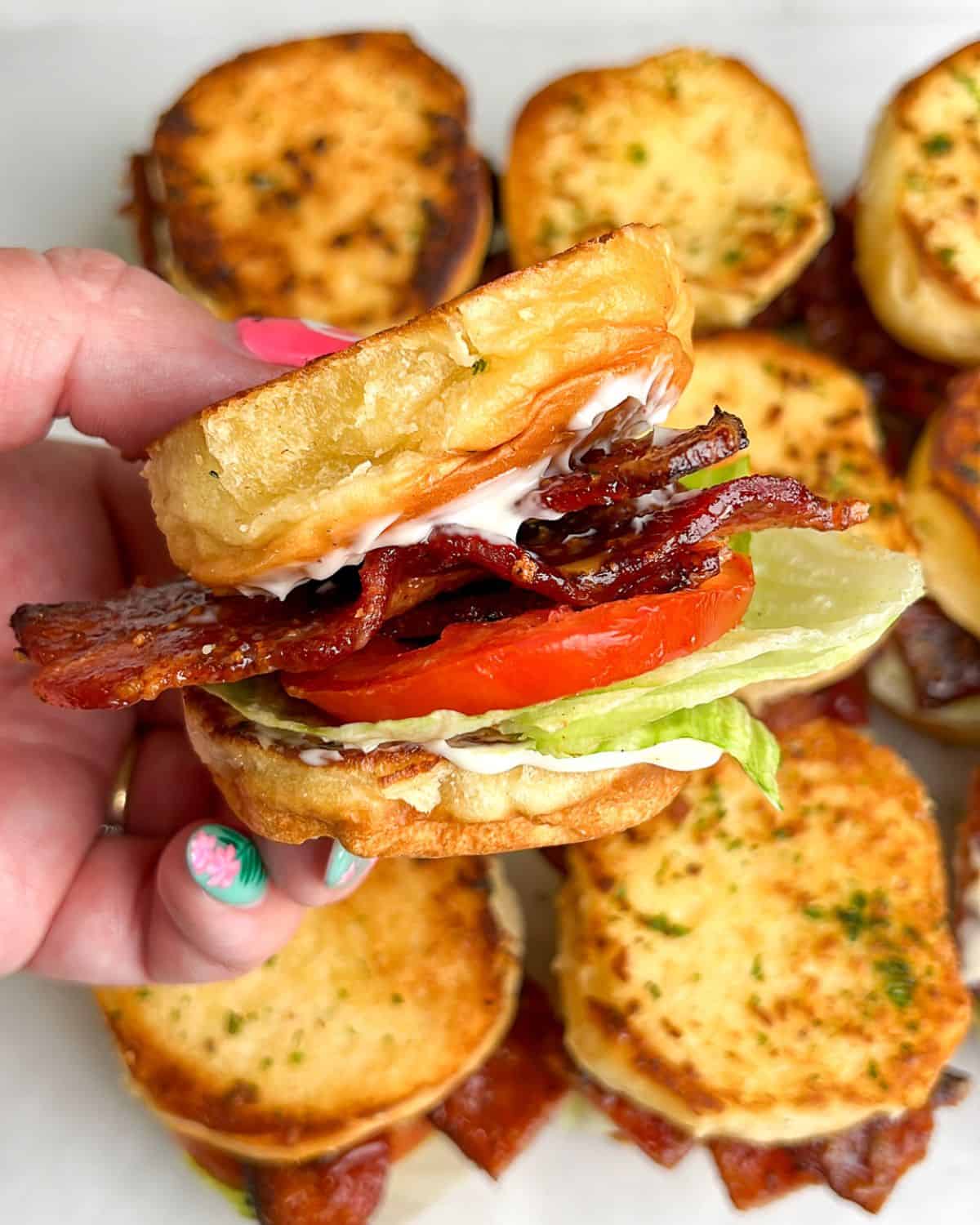 blt sliders sitting on the table and held in hand