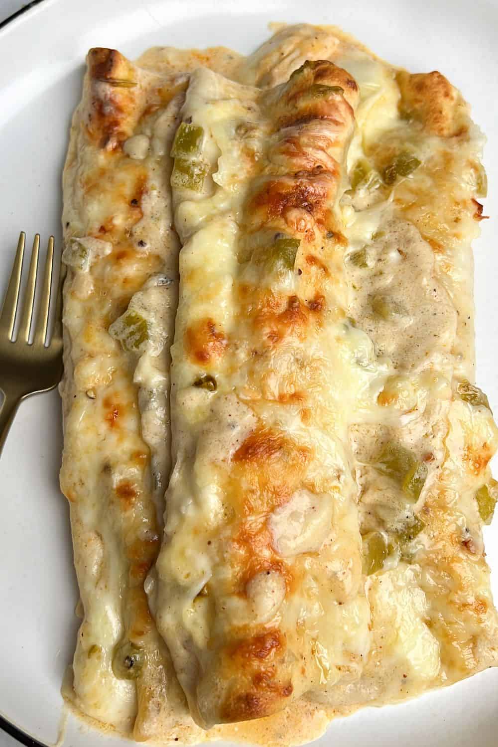 three white chicken enchiladas sitting on a plate