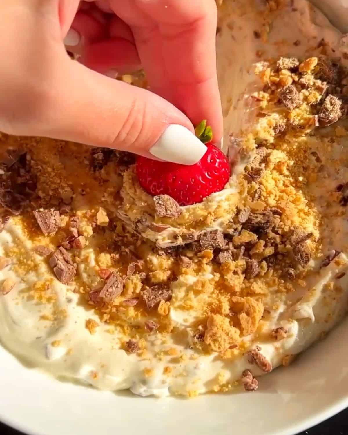 strawberry dipping into a no-bake s'mores dip