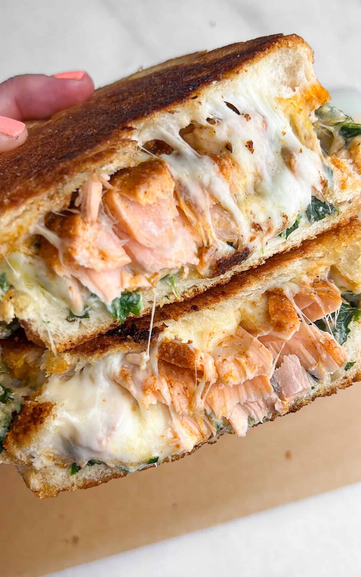 A salmon grilled cheese sandwich, cut in half to reveal the inside.