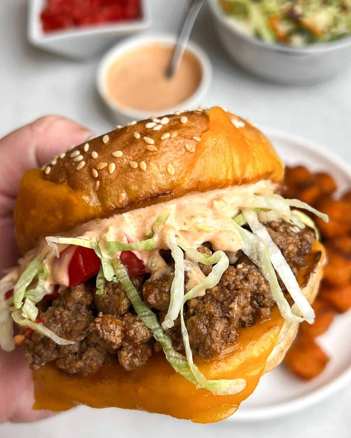 A hand holding a taco burger close to the camera.