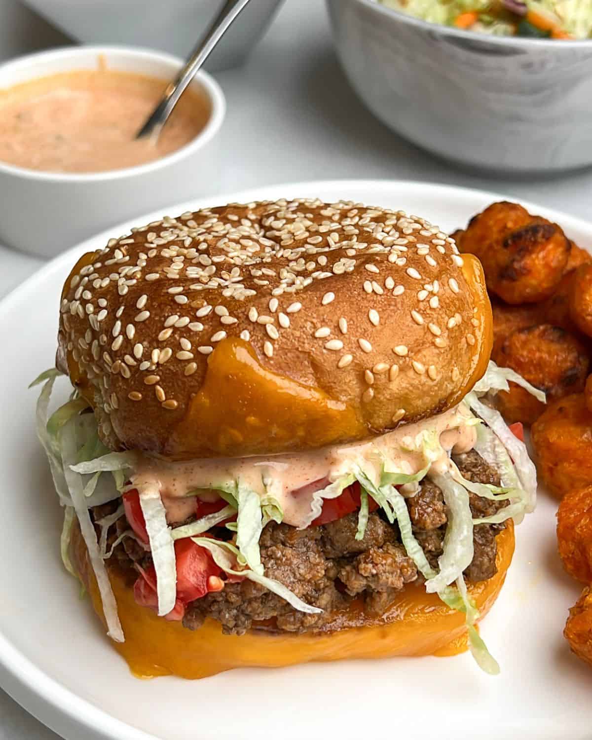 A taco burger on a plate with potatoes.