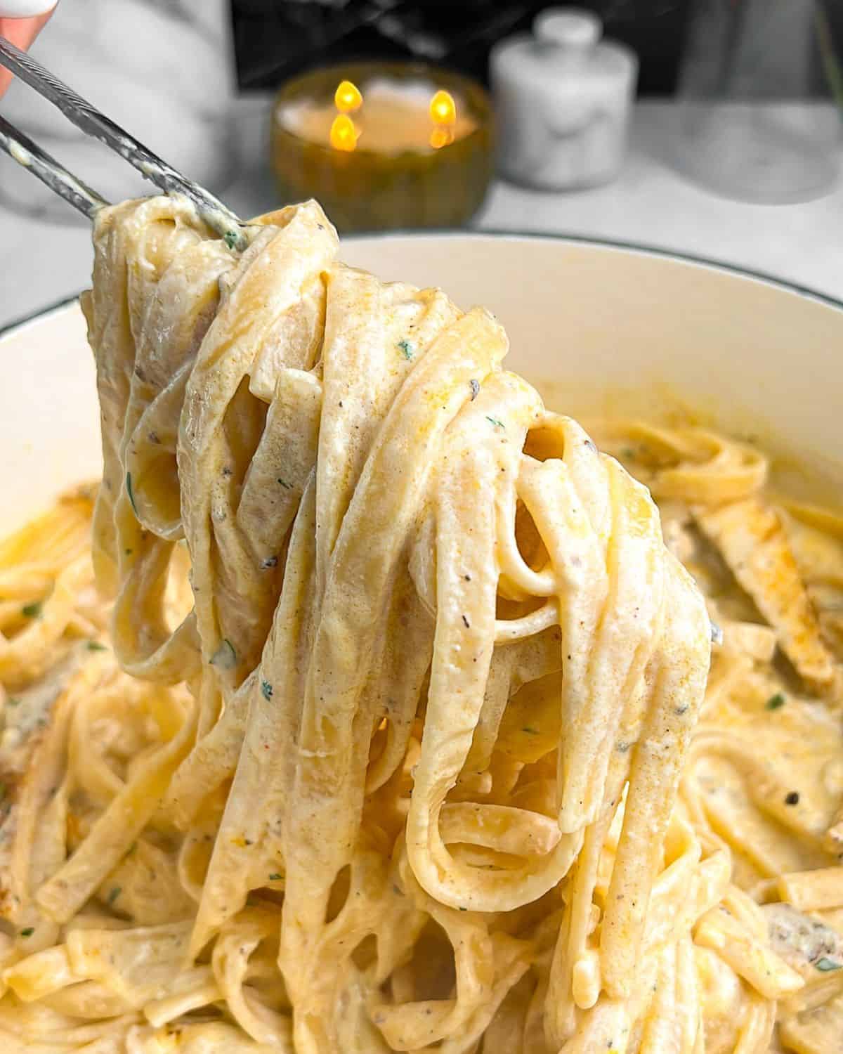 chicken alfredo noodles being pulled out of a pan