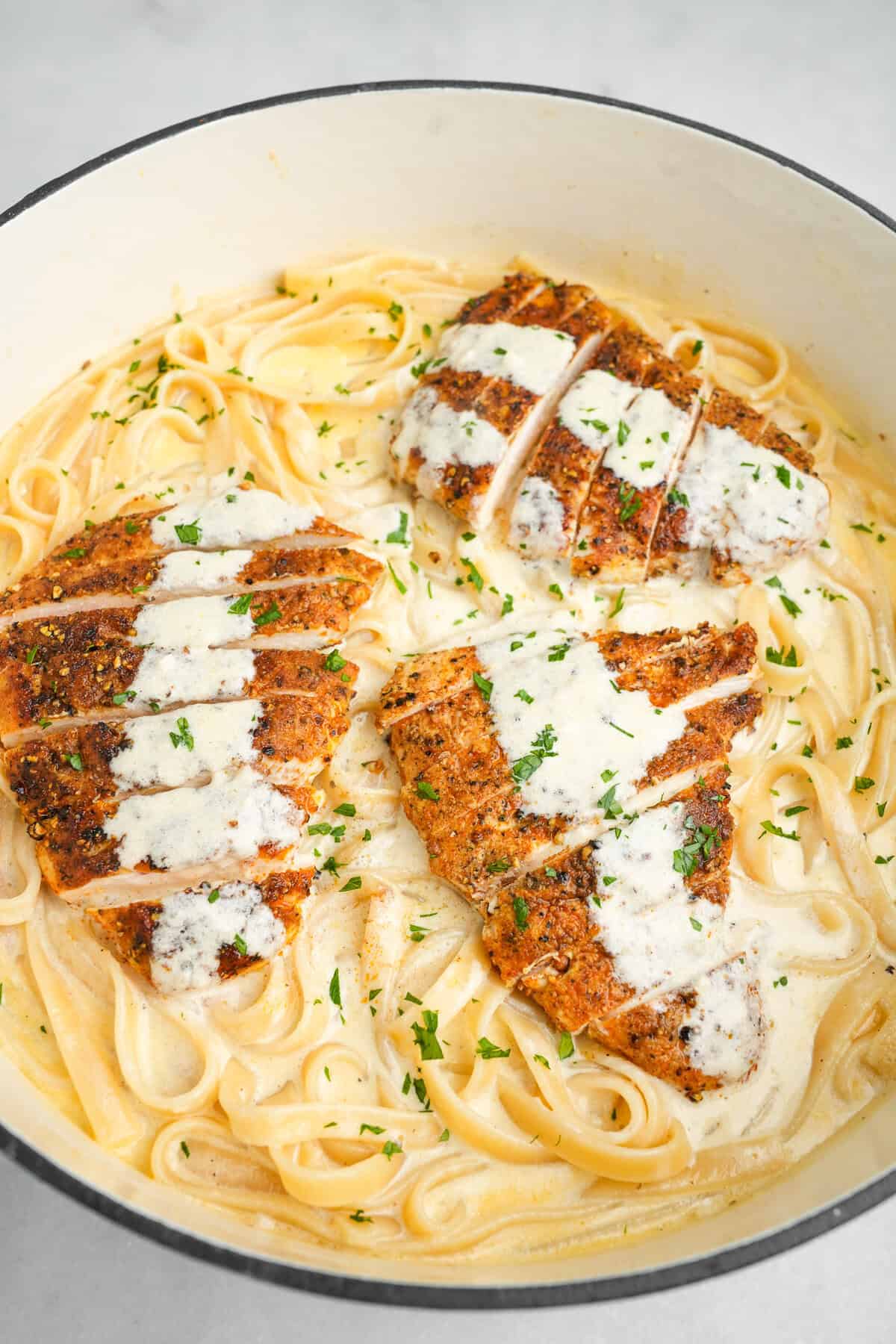 Make Olive Garden’s Chicken Alfredo at home with just a handful of ingredients in under 30 minutes. Creamy, decadent, & garlicky! a pan of chicken alfredo sitting on the counter