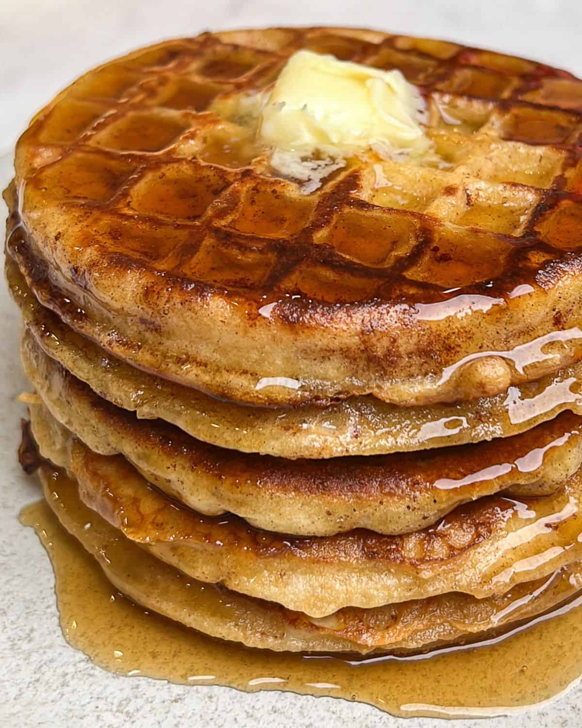 Close-up image of a stack of French toast waffles with butter and syrup.