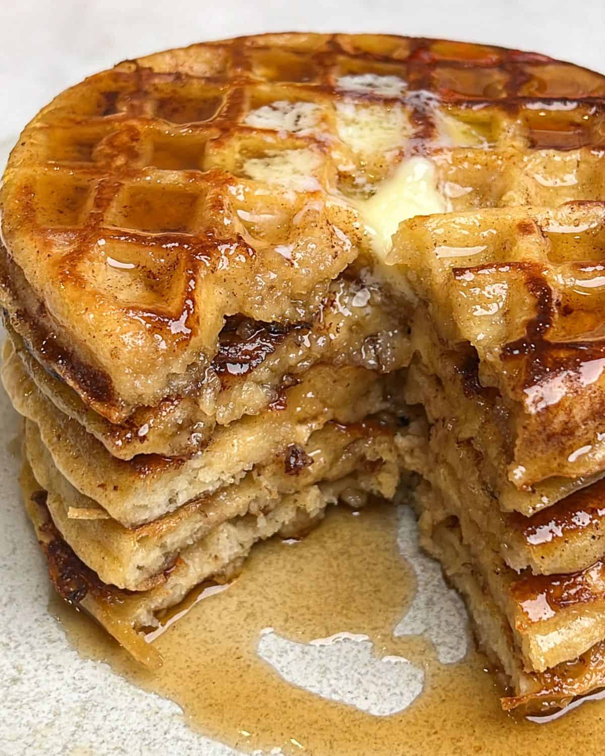 A stack of French toast waffles with a bite taken out of it.