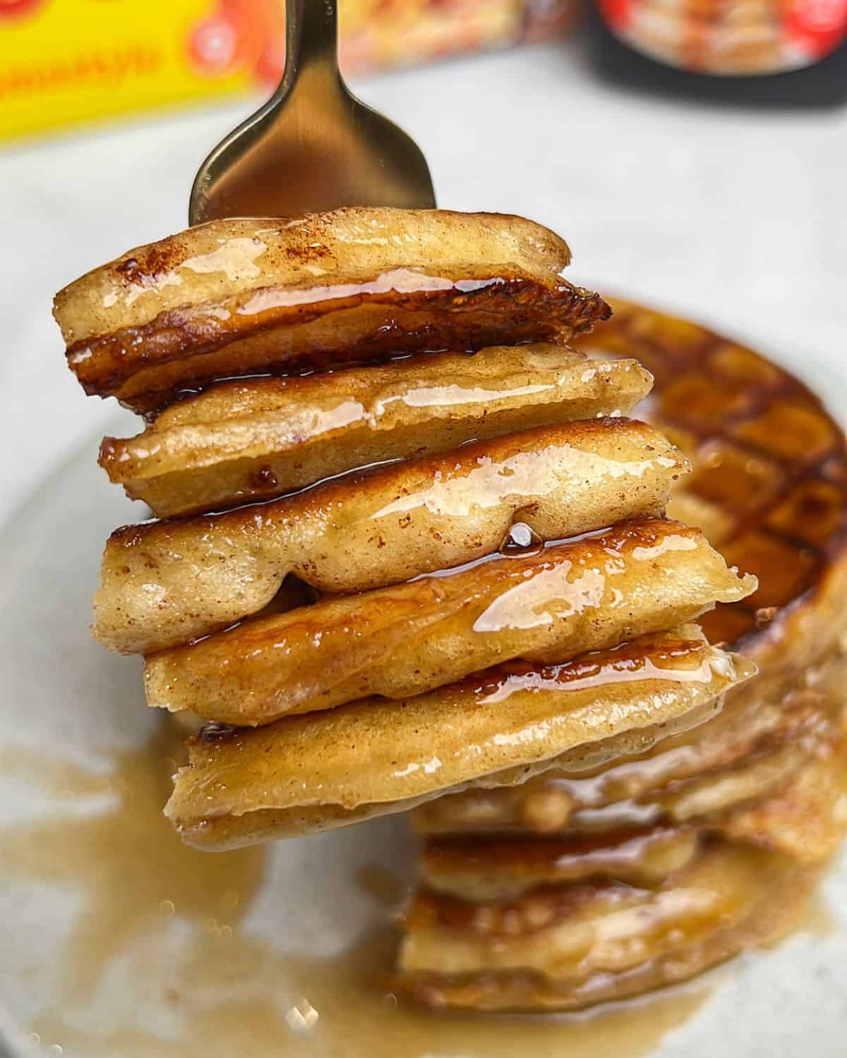 A fork holding a bite of French toast waffles up to the camera.