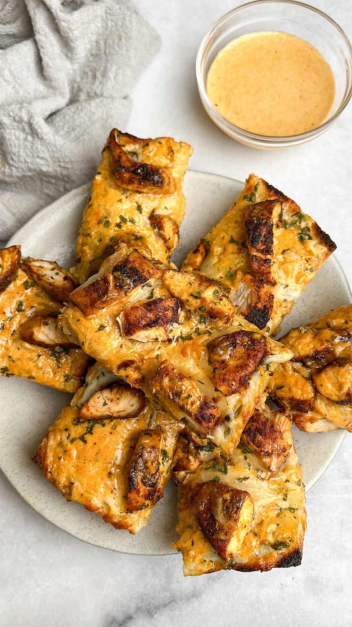 Pieces of chicken alfredo garlic bread stacked on a plate.