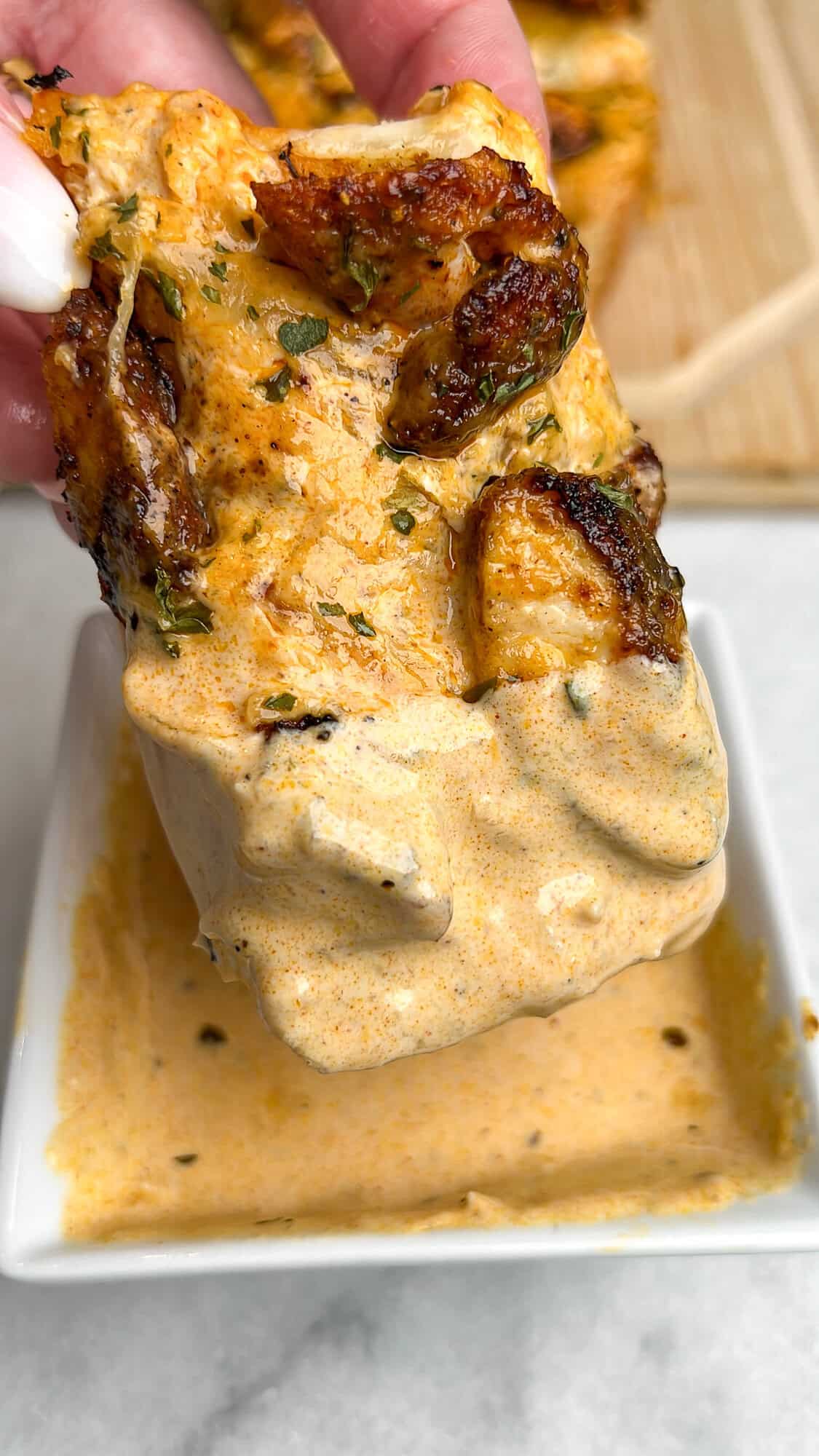 Dipping chicken alfredo garlic bread in alfredo sauce.