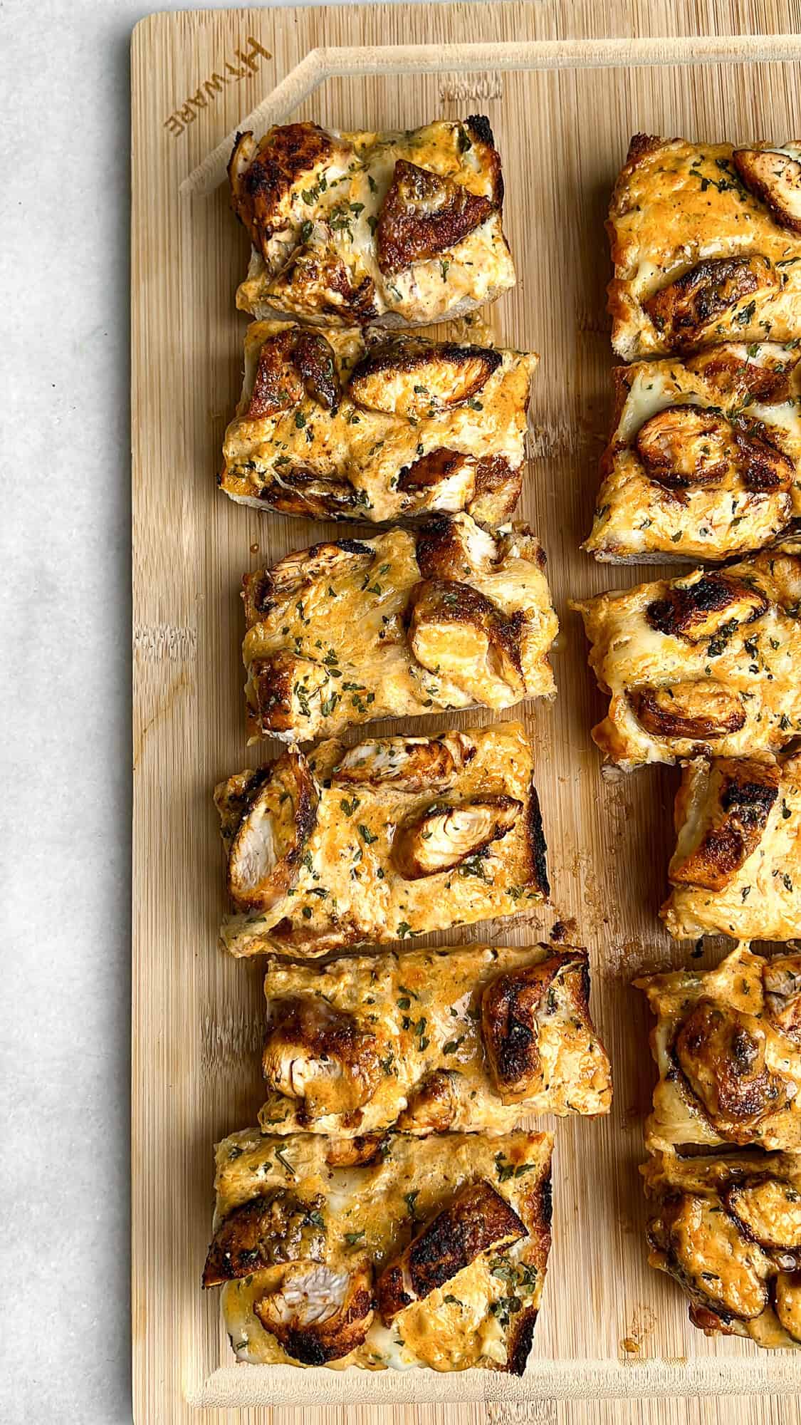 Chicken alfredo garlic bread on a cutting board sliced into pieces.