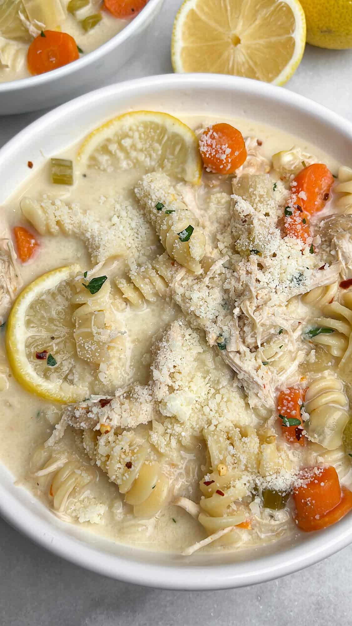 Slow-cooker creamy chicken noodle soup is finished with cream, Parmesan, and fresh lemon. It's a fun spin on a classic comfort food fave. A bowl of creamy chicken noodle soup sprinkled with parmesan.