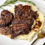 Red wine pot roast over mashed potatoes with a sprig of rosemary.