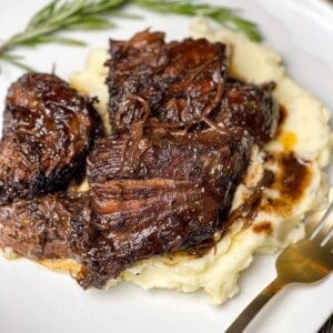 Red wine pot roast over mashed potatoes with a sprig of rosemary.