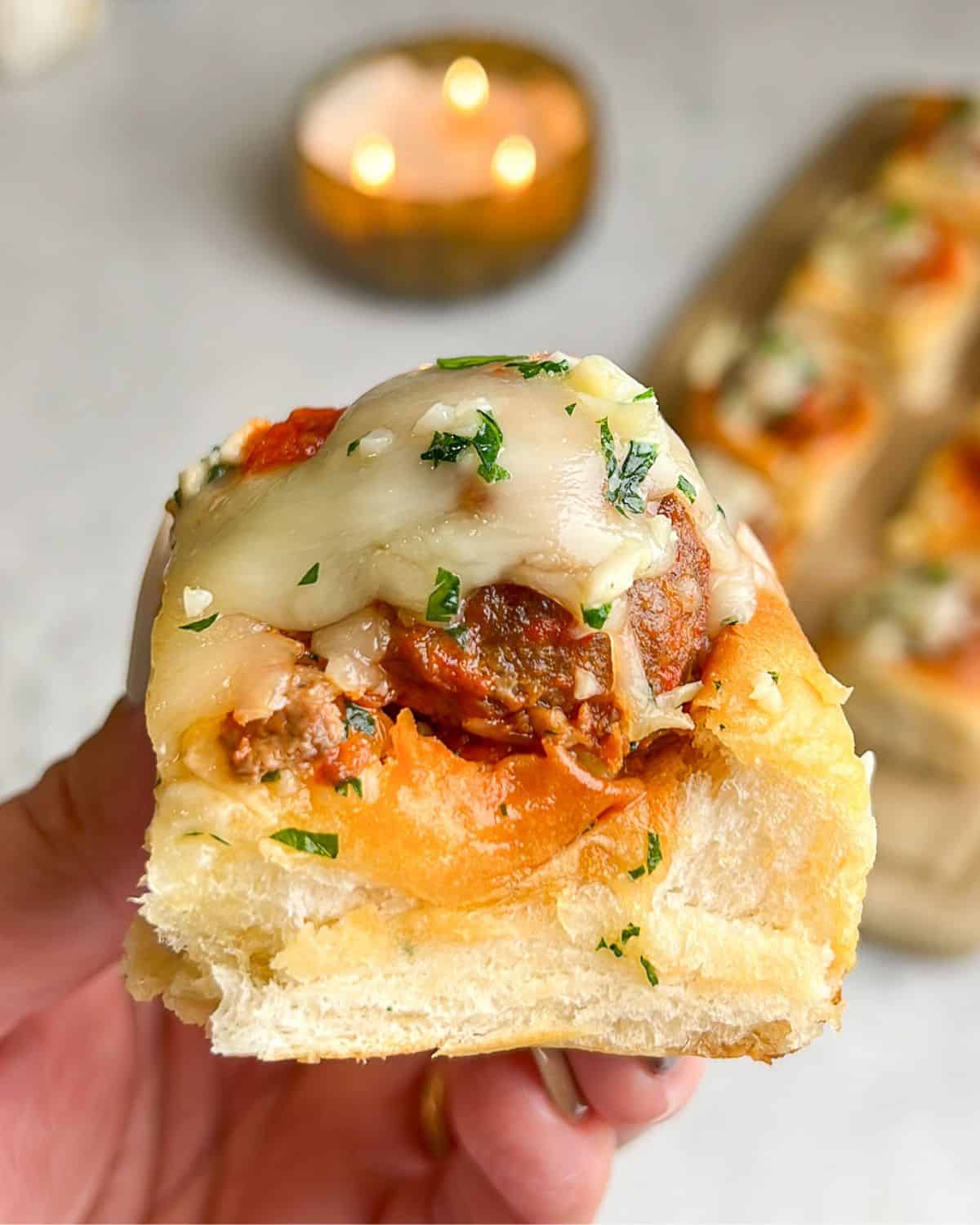hand holding a meatball slider over the counter