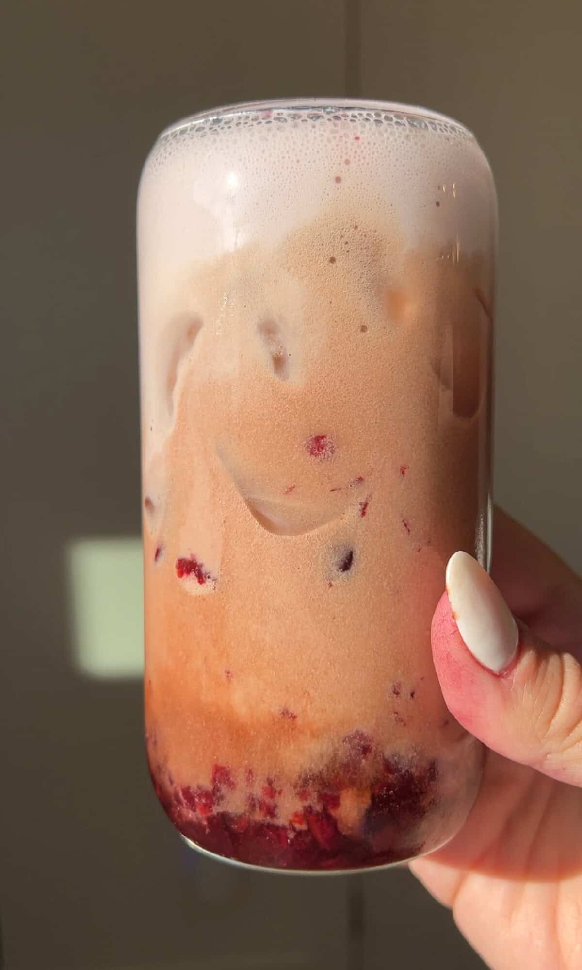 a hand holding a glass of cherry pie dr pepper