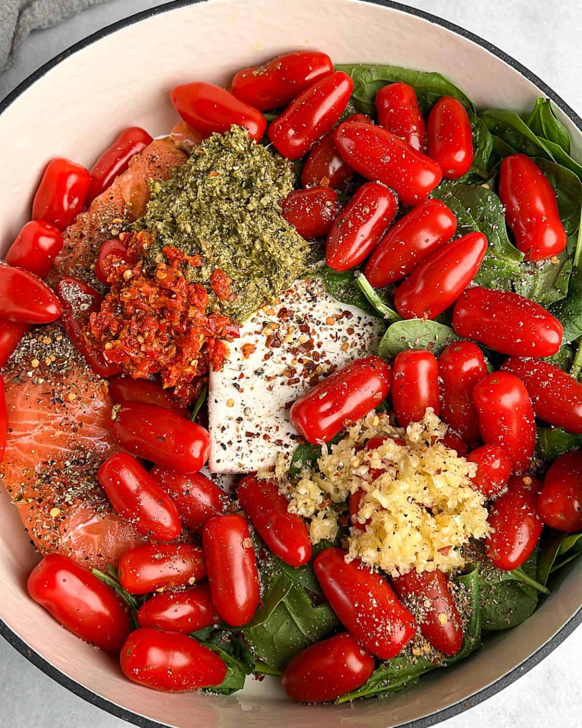 This one-pan feta tomato pasta with flaky salmon is loaded with juicy roasted tomatoes and wilted spinach, all tossed in a creamy feta sauce. A pan loaded with salmon, feta, tomatoes, spinach, garlic, and more to make baked feta tomato pasta.