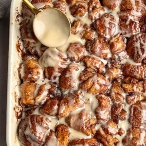 Drizzling frosting over cinnamon roll bites.