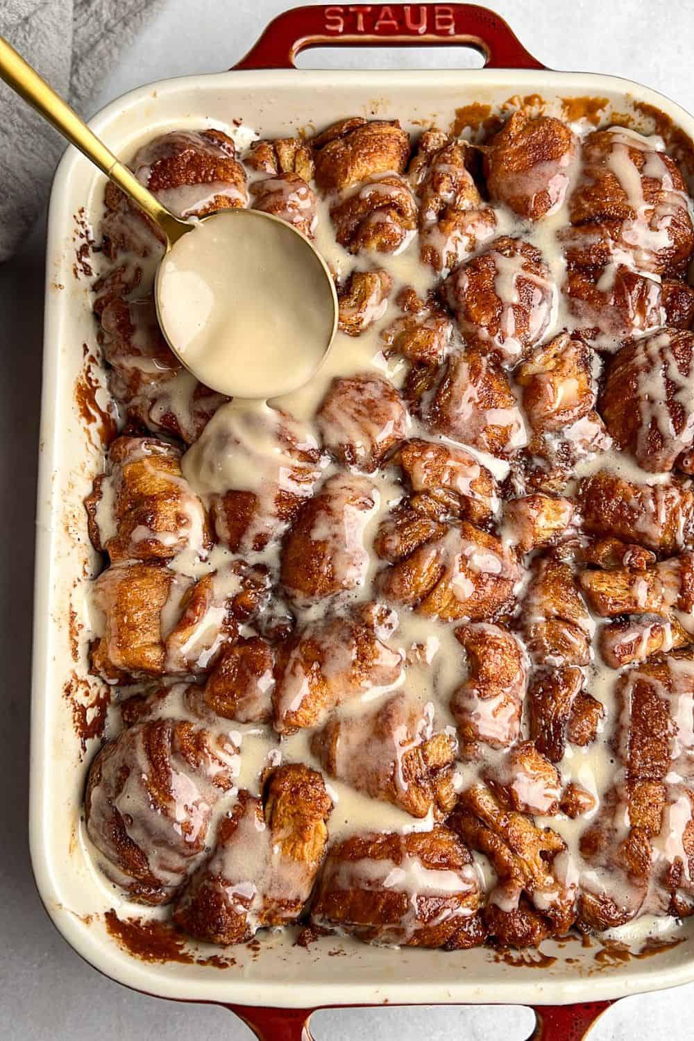 Drizzling frosting over cinnamon roll bites.