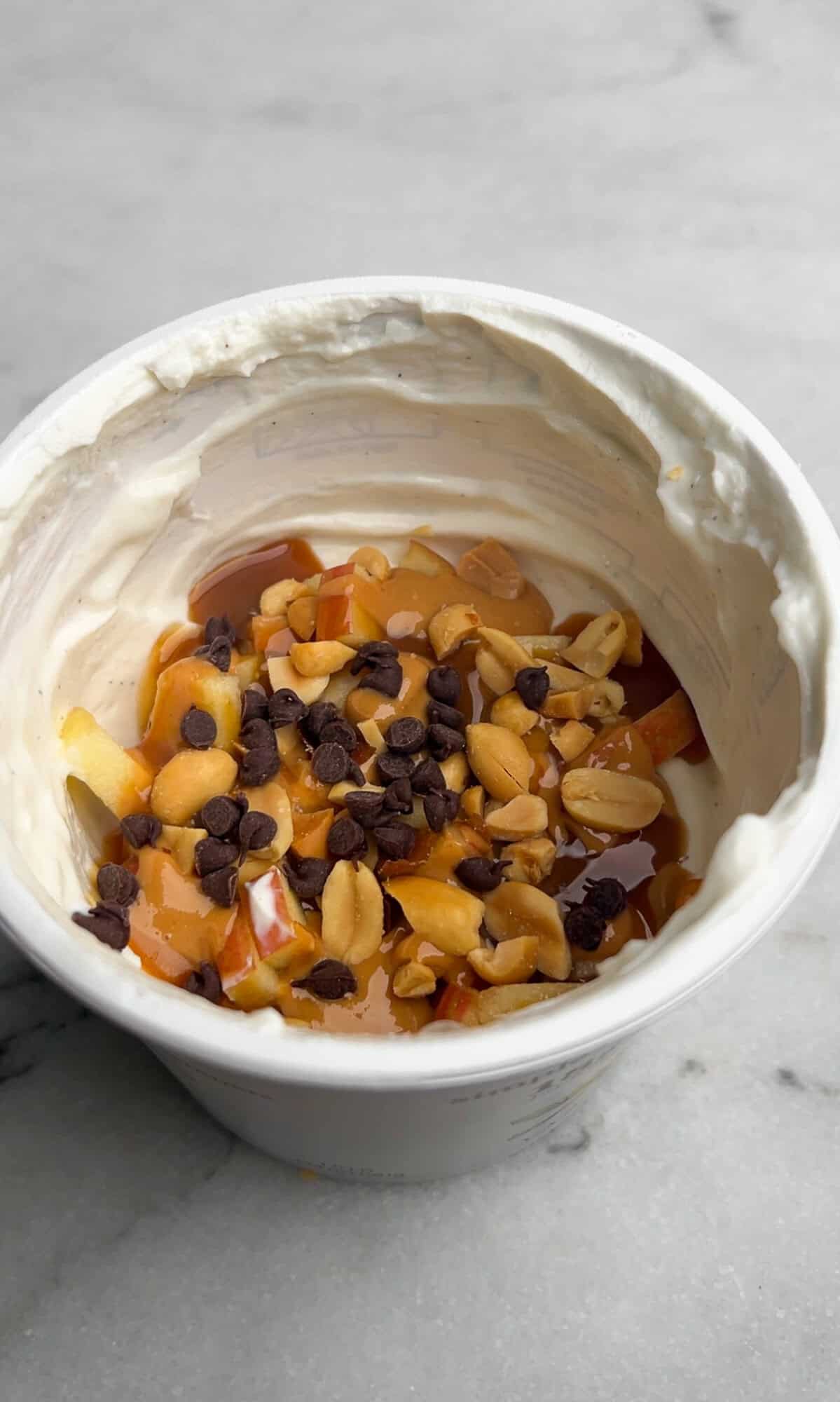 an alternate version to make snickers apple salad, layering the ingredients into a tub of yogurt