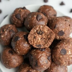 A pile of peanut butter protein balls on a plate. Obe has a bite taken out of it.