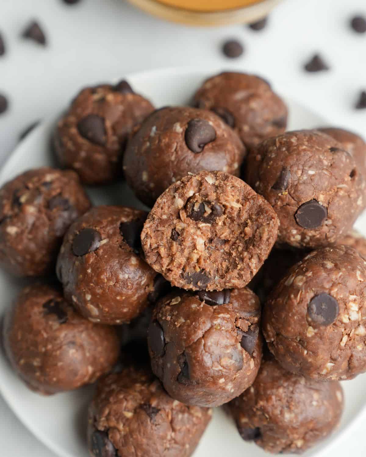 A pile of peanut butter protein balls on a plate. Obe has a bite taken out of it.