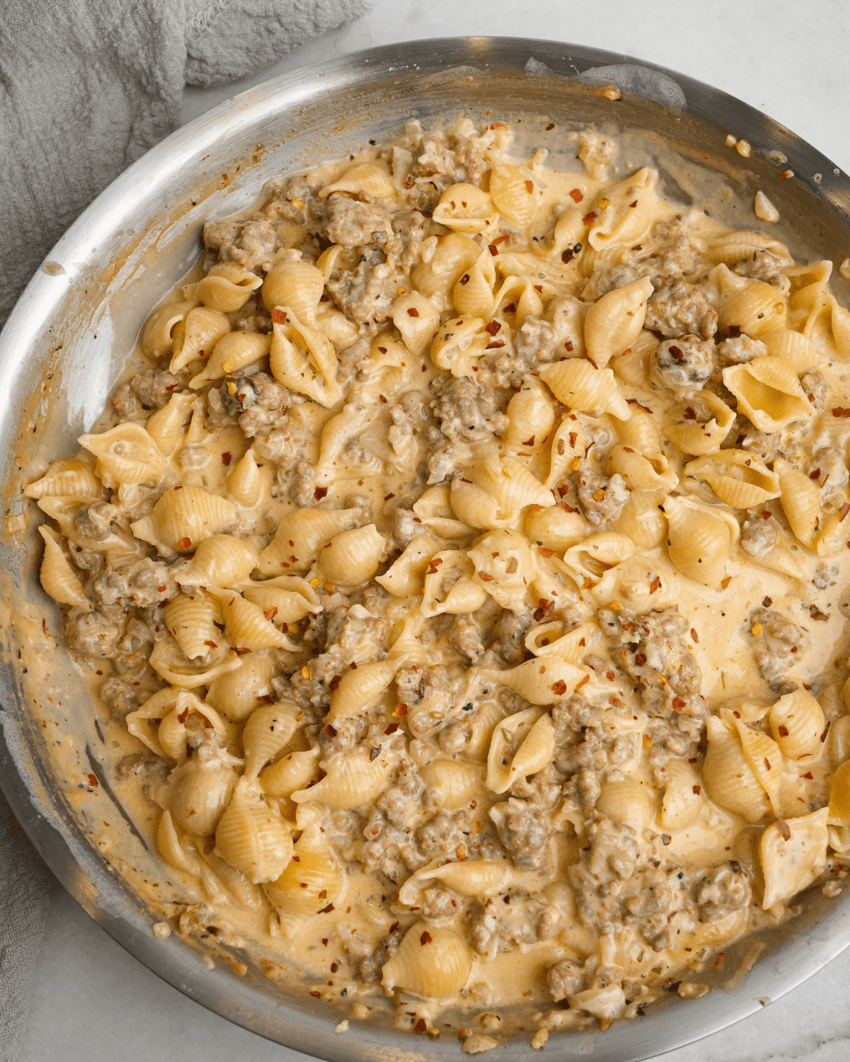 This creamy, spicy Italian sausage pasta comes together in just 30 minutes, and the luscious, cheesy white wine sauce is to die for. Overhead image of a skillet full of Italian sausage pasta.