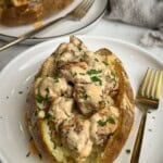 Chicken alfredo stuffed baked potatoes served on white plates.