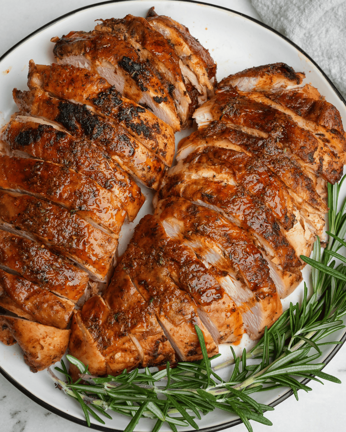 sliced turkey breasts on a plate with rosemary