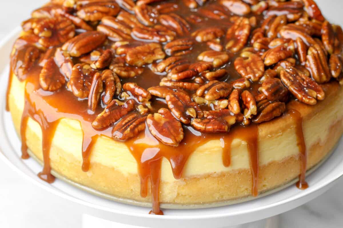 cheesecake on a stand with dripping bourbon caramel sauce with pecans