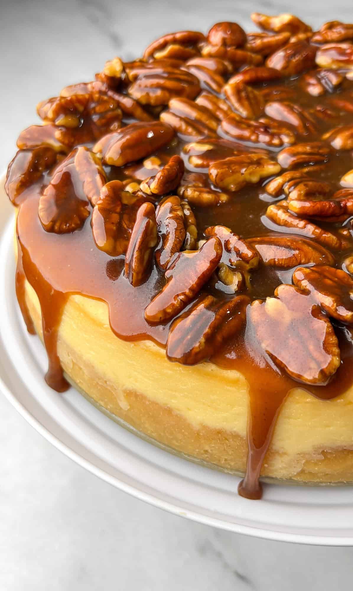 an up close shot of drippy caramel sauce dripping over a cheesecake