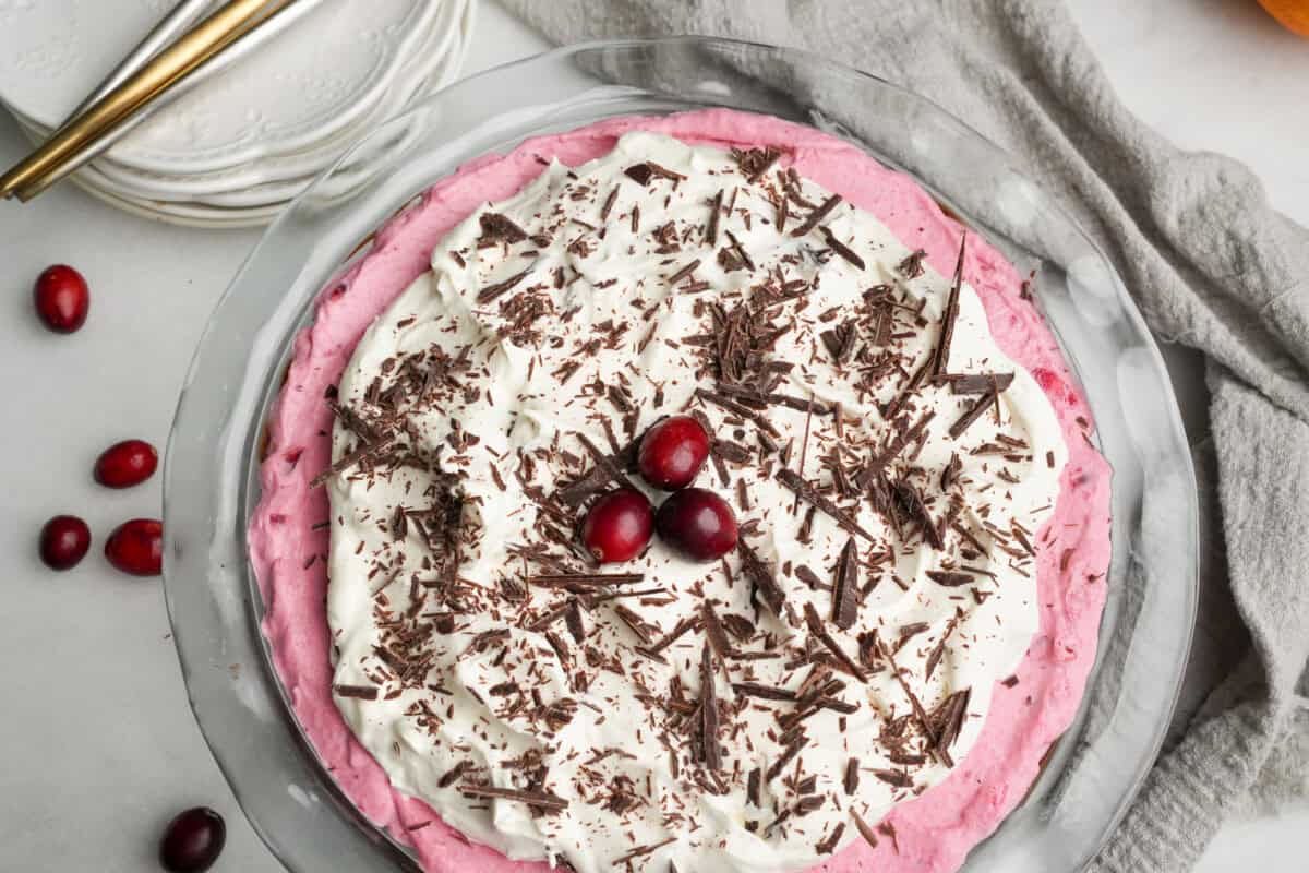 cranberry pie sitting on a table topped with whipped cream and chocolate shavings