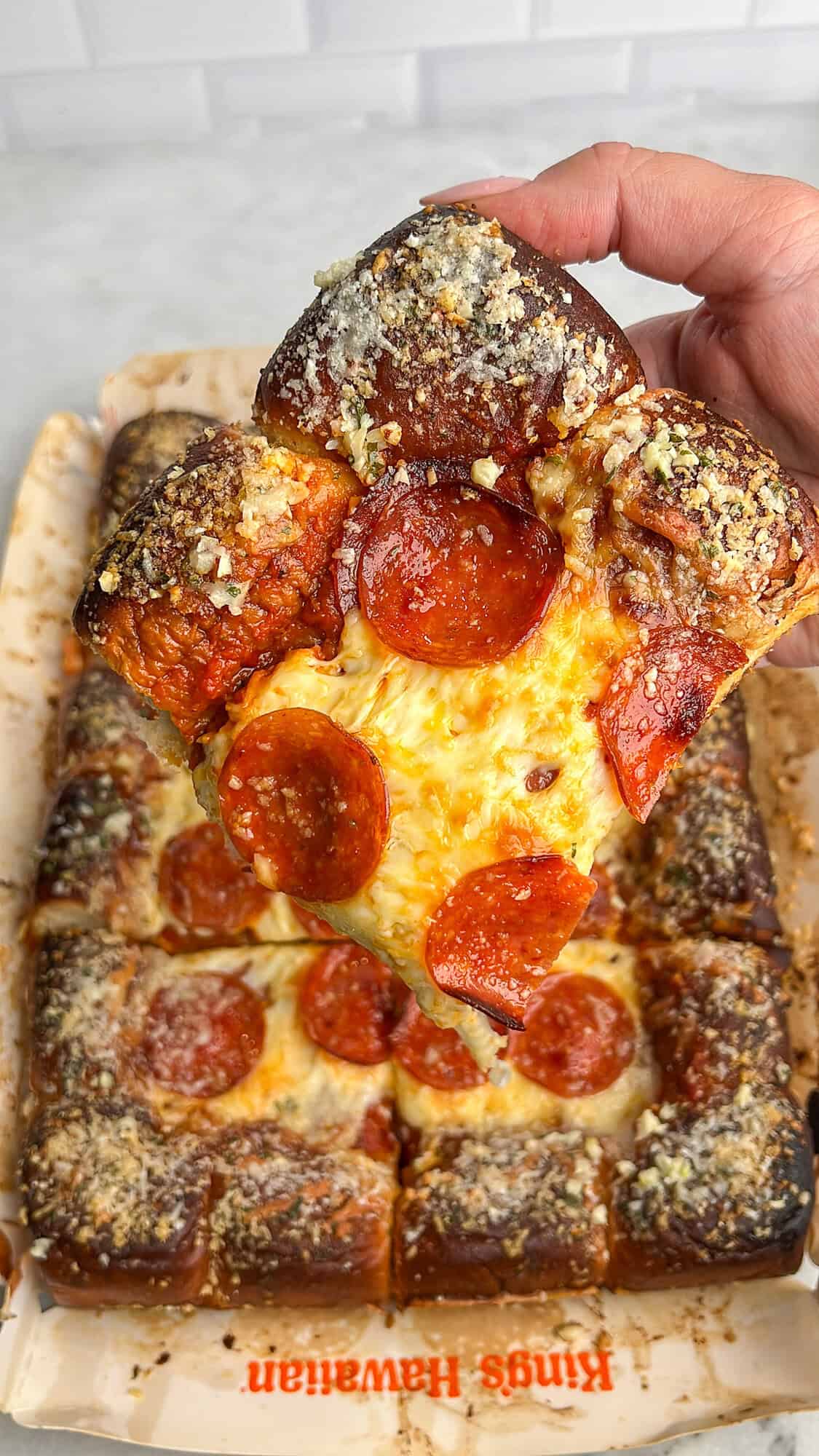 Hawaiian roll pizza slice being held in hand